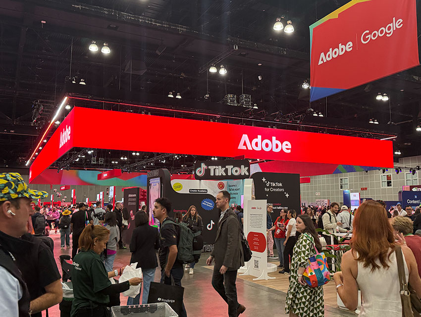 Adobe MAX 2025 Creative Park exhibition floor with Adobe and Google booths surrounded by attendees exploring new tools