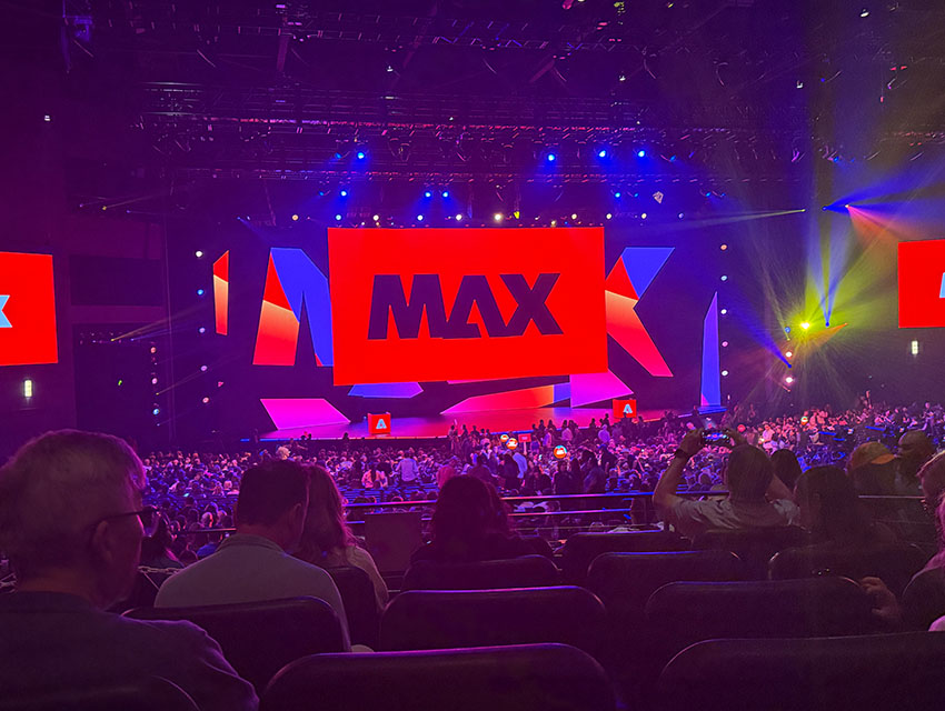 Adobe MAX 2025 keynote stage with bright red MAX logo and audience seated in Los Angeles convention hall