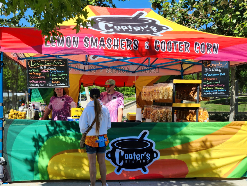 Cooter’s Catering Lemon Smashers and Kettle Corn custom food tent with bright rainbow canopy and tie-dye shirts