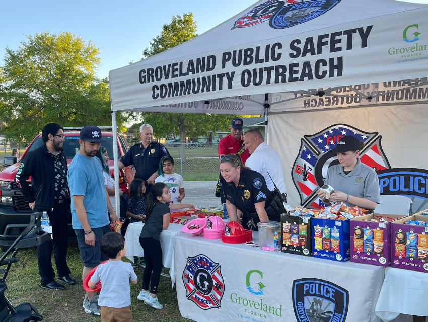 Groveland Public Safety officers handing out snacks and pink fire helmets to children under their custom tent
