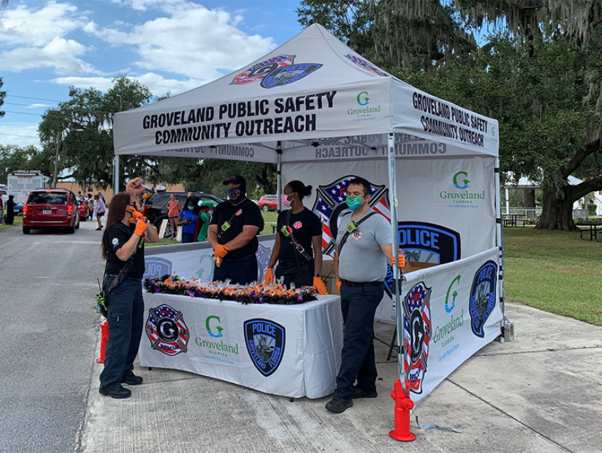 Groveland Public Safety officers and volunteers under their custom community outreach tent handing out items during a neighborhood event