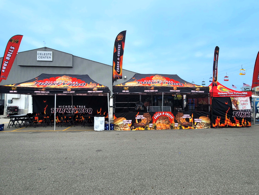 Hickory Tree Turkey BBQ multi-tent setup with custom flags and 10x20 dining area at a fairground
