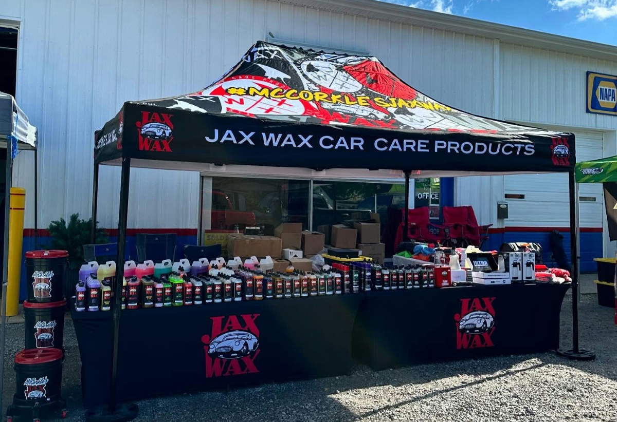Jax Wax custom booth tent with branded table covers and product displays at an outdoor event.