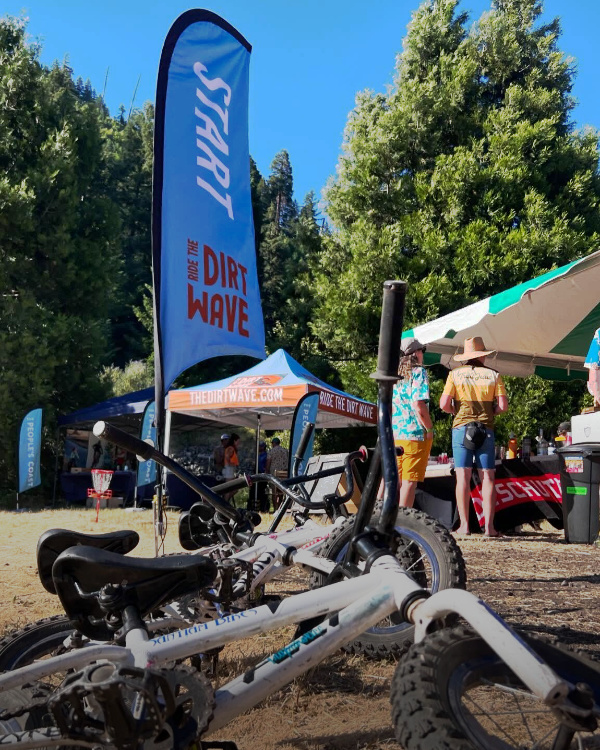 Ride the Dirt Wave start feather flag with custom pop up tent in the background at Oregon coastal mountain biking event