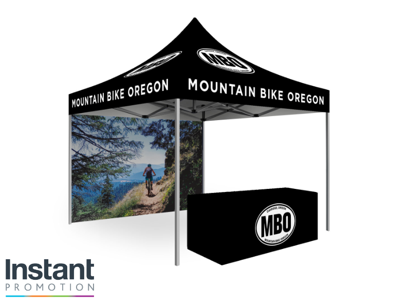 Mountain Bike Oregon Impact Pro Package free visual mockup showing custom pop up tent with black Trader Series frame fitted table cover and full color back wall