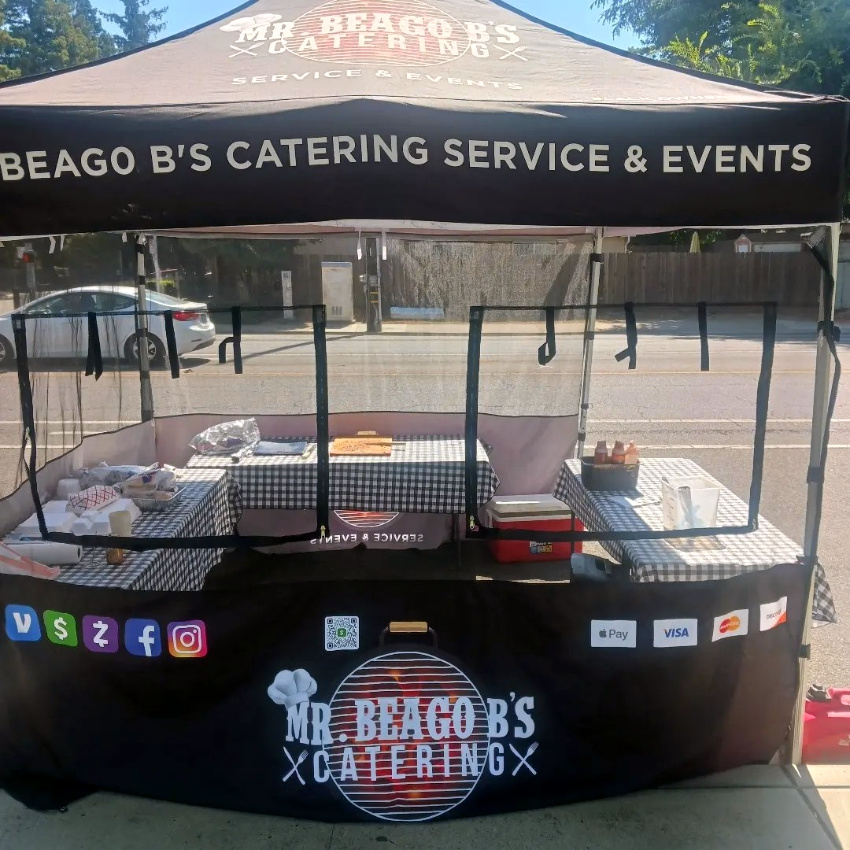 Mr. Beago B’s Catering custom tent featuring branded mesh walls and open side for condiments and sauces