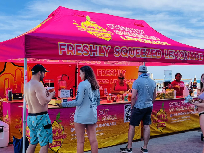 Vendor Pro tent setup for Oh Lemons featuring vibrant pink and yellow dye-sublimated graphics across canopy, back wall, and counters